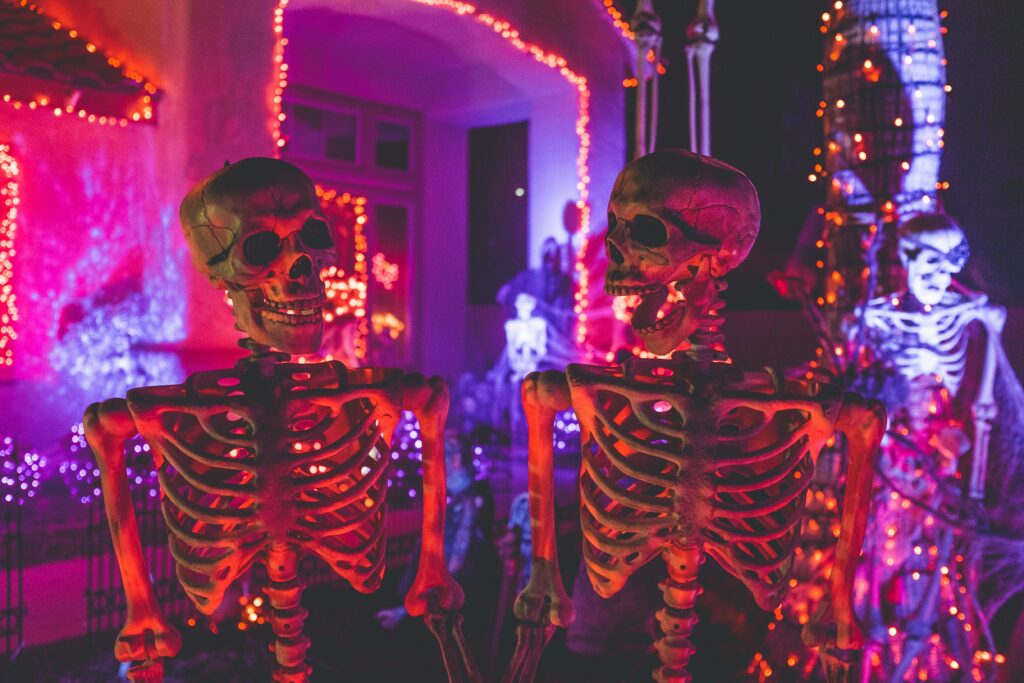 An Unplash image of two skeletons outside of a Halloween house. 